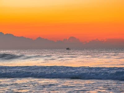 Boat sailing in the ocean at sunset