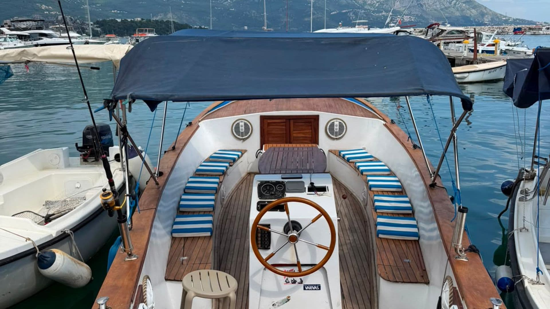 Classic wooden boat with blue canopy moored in Budva marina