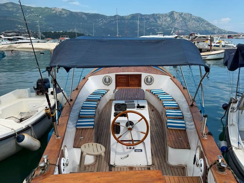 Classic wooden boat with blue canopy moored in Budva marina