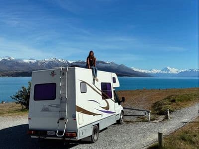 Ford Transit motorhome parked by a lake with snowy mountains in New Zealand