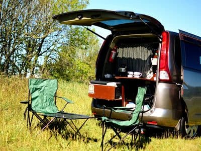 Serenity sleepervan with open tailgate kitchen and camping chairs