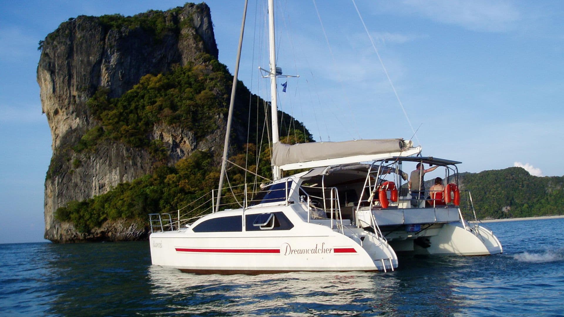 Sailing catamaran Dreamcatcher at anchor beside a limestone rock, Gulf of Thailand