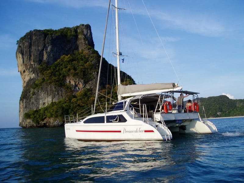 Sailing catamaran Dreamcatcher at anchor beside a limestone rock, Gulf of Thailand