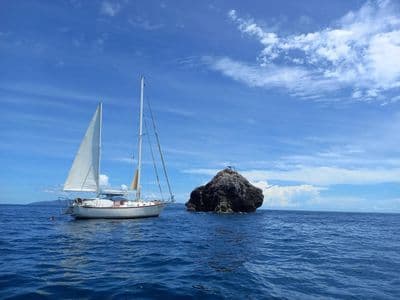 Geronimo ketch sailing past a rock in deep blue sea
