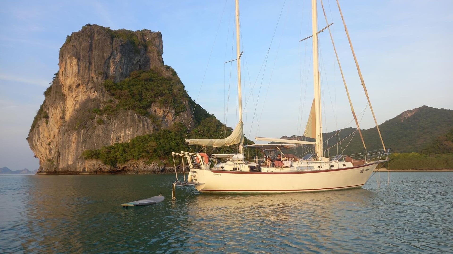 Classic ketch anchored beside a limestone rock on an overnight sailing cruise