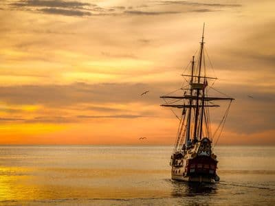 Boat sailing at sunset near cave coastline