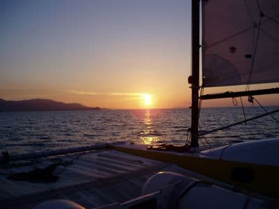 Guests watching the sunset from the deck of a sailing yacht