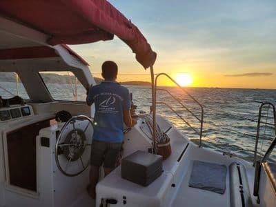Skipper at the helm sailing towards the sunset